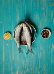 Fresh raw fish in a bowl on a blue wooden background. Top view.