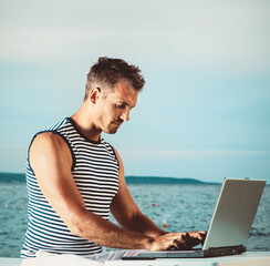 Man on the beach working on the laptop 