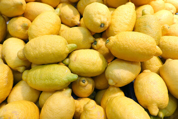 Crop of many ripe yellow lemons fruits in the showcase as background top view close up