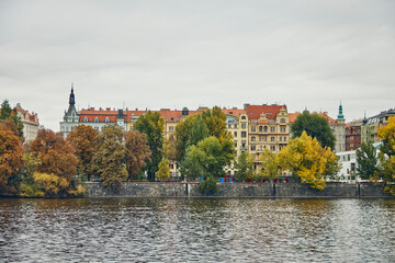 Obraz premium Historic building on the embankment of Vltava behind the autumn trees.