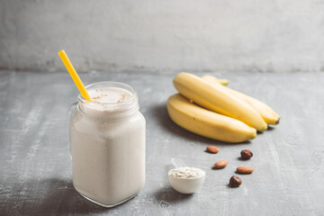 Banana smoothie with protein powder and nuts in a glass jar, healthy eating concept