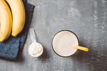 Banana smoothie with protein powder in a glass, top view, healthy eating concept