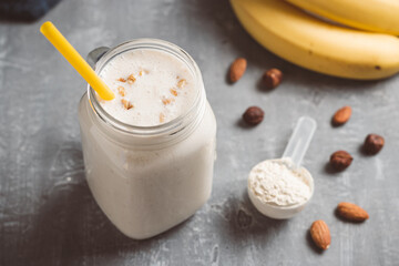 Banana smoothie with protein powder and nuts in a glass jar, healthy eating concept