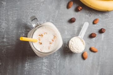 Banana smoothie with protein powder and nuts in a glass jar, top view, healthy eating concept