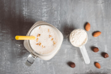 Banana smoothie with protein powder and nuts in a glass jar, top view, healthy eating concept