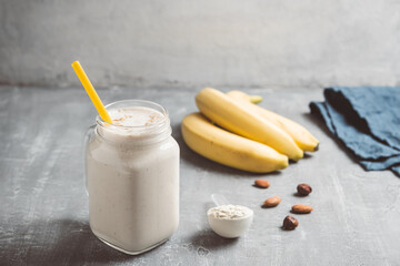 Banana smoothie with protein powder and nuts in a glass jar, healthy eating concept