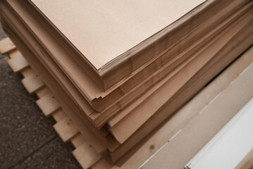 Fototapeta premium Brown paper for packaging and printing on it, kraft paper in piles lies in the warehouse of the printing industry, top view, development of the printing industry
