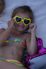 Girl with heart-shaped glasses and closed eyes smiling