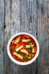 Tomato soup with noodles on wooden table
