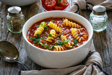 Tomato soup with noodles on wooden table
