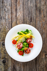 Tasty salad - prosciutto crudo, melon and fresh vegetables on wooden table
