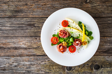 Tasty salad - prosciutto crudo, melon and fresh vegetables on wooden table
