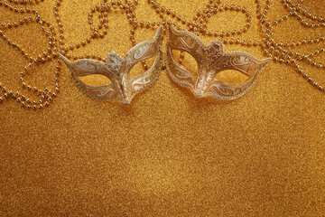 Mardi gras or carnival mask with beads on gold glowing background. Venetian mask.