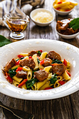 Pasta with roasted pork loin, spinach and parmesan on wooden table 