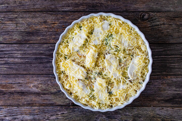 Uncooked noodle casserole with roast pork loin, mozzarella cheese, bechamel sauce and spinach on wooden table
