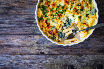 Noodle casserole with roast pork loin, mozzarella cheese, bechamel sauce and spinach on wooden...