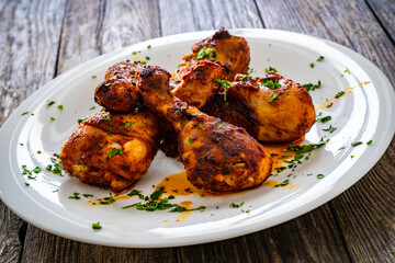 Barbecue chicken drumsticks with French fries on wooden table
