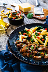 Pasta with roasted pork loin, spinach and parmesan on wooden table
