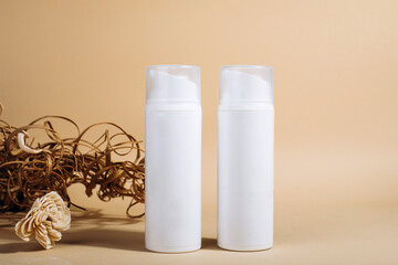 Plastic white bottles with pump for cream or lotion on glass plate for product presentation. Skin care cosmetic in top view on yellow background with palm leaves shadow. Beauty concept for face care