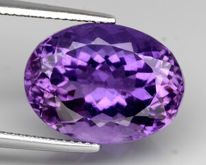Natural gemstone purple amethyst on gray background