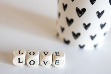The word Love made up of wooden cubes and a paper glass with black hearts isolated on a white background