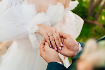 a man's hand holds a woman's hand with a wedding ring on her finger. 