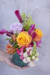 Arreglo floral en botella de vidrio azul con rosas y follajes finos