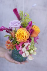 Arreglo floral en botella de vidrio azul con rosas y follajes finos