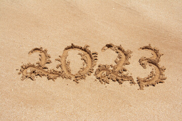 Year 2023 handwritten on sand beach. Selective focus.