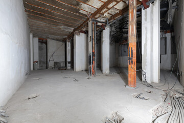 Interior premises under construction with raw cement floors and half finished electrical pipes with...