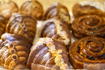 Fresh delicious buns and croissants with nuts are on the counter in the bakery. French croissants with pistachios and hazelnuts top view. Homemade cakes.