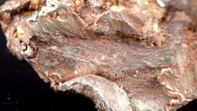 Rotating Of An Iron Meteorite. black background on a mirror base. Close-up. Macro. Rust on the surface