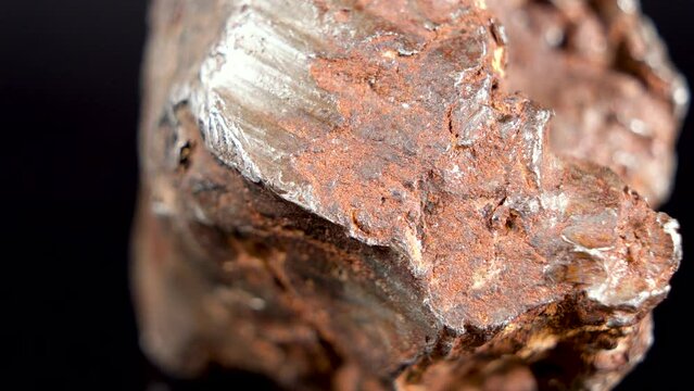 Rotating Of An Iron Meteorite. black background on a mirror base. Close-up. Macro. Rust on the surface