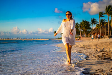 Beach holiday - woman walking on sunny, tropical beach in the morning 

