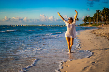 Beach holiday - woman walking on sunny, tropical beach in the morning 

