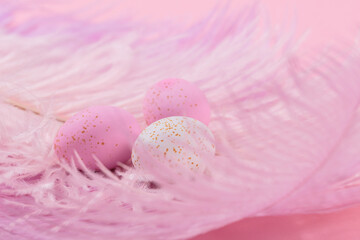 Easter candy chocolate eggs and almond sweets lying on pink feathers background. Happy Easter concept.
