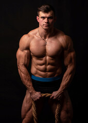 Fototapeta na wymiar Muscled Male Model Flexes with Large Rope in Studio Setting