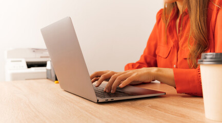 Faceless shot of a young woman working hard at the laptop in her office.
