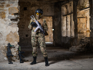 Fototapeta premium A woman in an army uniform holds a firearm in an abandoned building.