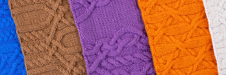 Knitted blue, lilac, brown, orange and beige background. Large knitted fabric with a pattern. Close-up of a knitted blanket. Banner
