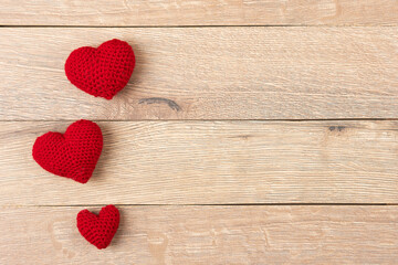 Red knitted hearts on a wooden background. Happy Valentine's Day, Mother's Day and birthday greeting card.