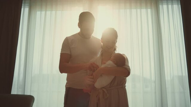 New parents young couple mother and father standing with baby against sun and learn to take care about newborn baby at home