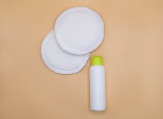 Face cream or lotion and make up removing foam with cotton pads on beige background. 