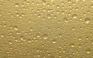 Fototapeta na wymiar Round water drops on the gold chrome surface of the wall.Golden background in raindrops.Chrome-plated metal.