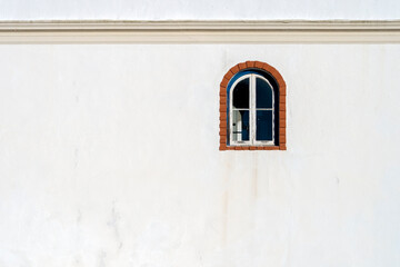 Old building with an arched window on a white rendered wall.
