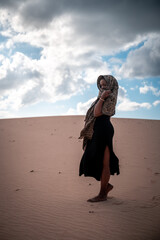 African woman with black dress and scarf in the desert