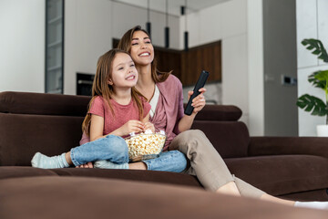Mother with daughter watching watching television in living room