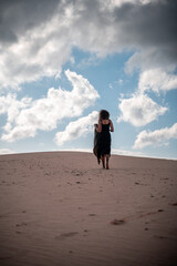 African girl in black dress walking in the desert