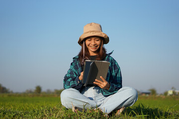 Asian female farmer delighted with rice growth target. Computer analysis