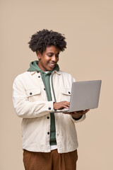Happy smiling African American teenager student holding laptop using computer technology presenting elearning, remote education and online webinars isolated on light beige background. Vertical